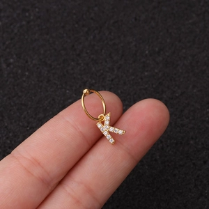 Vue macro d'une boucle d'oreille dorée avec pendentif lettre K et zircons étincelants