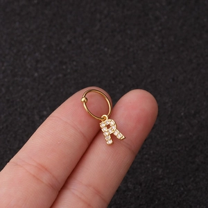 Détail d'une boucle d'oreille dorée avec pendentif lettre R serti de zircons brillants
