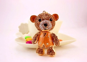 Detail of cute teddy bear keychain featuring champagne rhinestones and orange enamel flowers