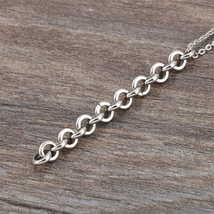Collier à maillons en acier inoxydable argenté poli sur une surface en bois texturé