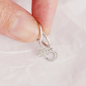 Detail shot of asymmetric 925 silver star and moon earrings with pavé zircon stones