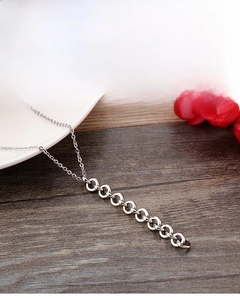 Gros plan sur les anneaux argentés entrelacés d'un collier minimaliste en acier inoxydable