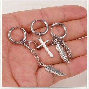 Detailed view of silver stainless steel earrings featuring cross, feather and chain charms