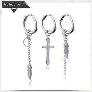 Detailed macro view of silver titanium steel earrings with feather and cross charms