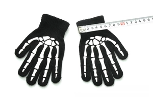 Detailed view of black knitted skeleton gloves for kids showing width measurement with a tape
