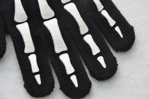 Close-up of winter knitted gloves with white glow-in-the-dark skeleton pattern