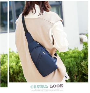 Outdoor lifestyle shot of a navy blue nylon crossbody sling bag with headphone jack