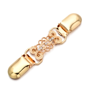 Macro detail of golden cardigan clip with hollow patterns and sparkling rhinestones
