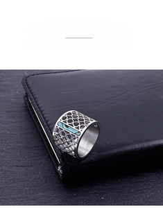 Macro detail of cut-out stainless steel ring with abalone shell inlay on black leather