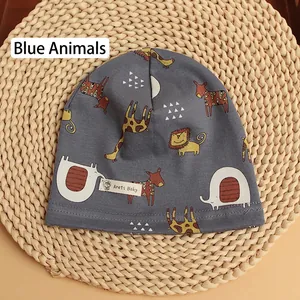 Detail of blue-grey cotton baby beanie featuring cartoon giraffe and lion prints