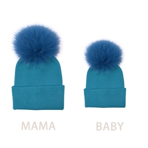 Set of matching parent and child cyan knit beanies with large fluffy fur pom poms