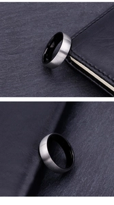 Detail of silver brushed steel ring with black enamel interior on leather background
