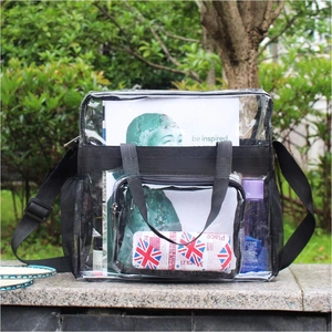 Outdoor view of clear PVC tote bag with black trim and adjustable shoulder strap