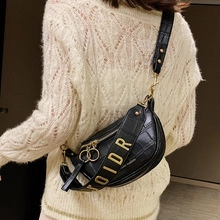 Détail du sac noir texture crocodile avec bandoulière dorée OIDR et chaîne