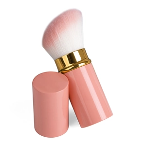 Dettaglio del pennello trucco retrattile rosa corallo con accenti dorati e setole morbide