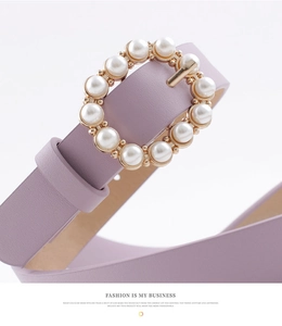 Close-up of lavender leather belt featuring a round gold buckle with pearl embellishments