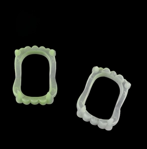 Detail showing two pairs of plastic vampire fangs in white and light green for Halloween