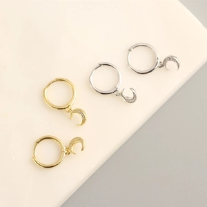 Macro shot of gold and silver crescent moon earrings with sparkling inlaid diamonds