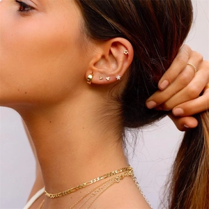 Detailed macro view of layered gold star earrings and matching necklaces on female model