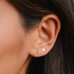 Close-up of elegant gold and silver hollow star earrings worn on a woman's ear