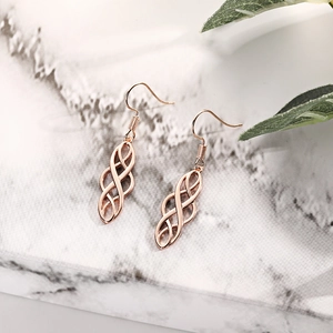 Detailed macro view of rose gold Celtic knot hollow drop earrings on marble background