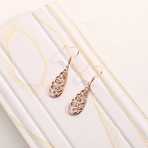 Detailed macro view of rose gold teardrop earrings with intricate filigree patterns