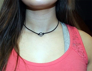 Detail of single black shell pearl necklace on hand-knotted black leather cord