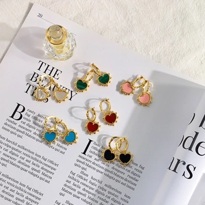 Flat lay of six colorful heart charm hoop earrings on a vintage magazine page