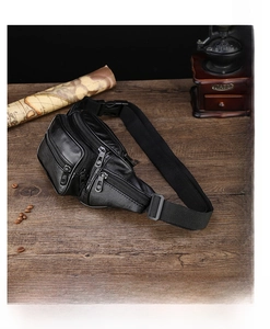 Macro view of multi-pocket black PU leather waist bag with zipper on vintage wood table