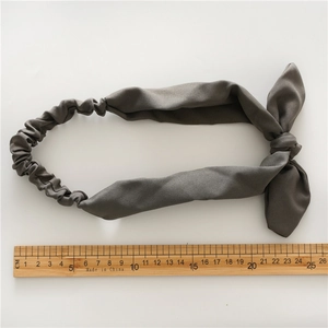 Grey bunny ear elastic headband with bow design for women, flat lay on white backdrop