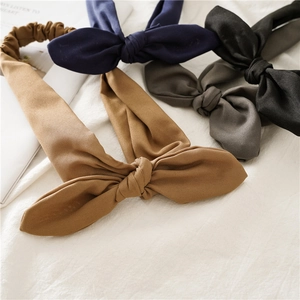 Detail of four colorful rabbit ear headbands with elastic bands on soft white fabric