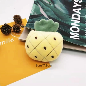 Detail view of a 9x7.5cm yellow plush pineapple brooch on a decorative background