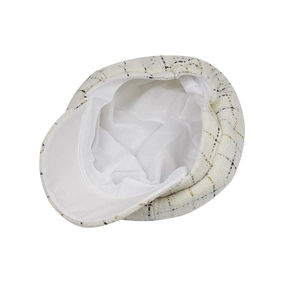 Détail de la casquette gavroche en tweed montrant le motif à carreaux et la doublure