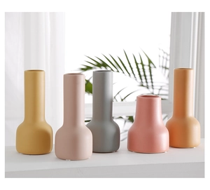 Jarrones de cerámica mate en colores Morandi en el alféizar de una ventana decorativa