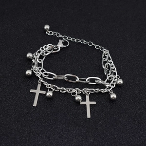 Detailed view of silver double-layered bracelet with cross pendant and metal beads