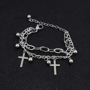 Double-layered stainless steel chain bracelet with cross and ball charms on dark background