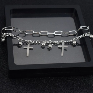Macro shot of silver double-layer bracelet with cross pendants and round beads in a black gift box