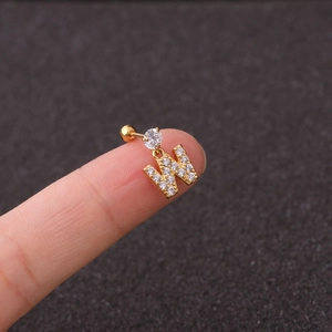 Detailed view of a gold 'W' initial ear stud with sparkling zircons on a fingertip