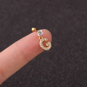 Close-up of a gold G-letter earring with sparkling cubic zirconia on a gray background