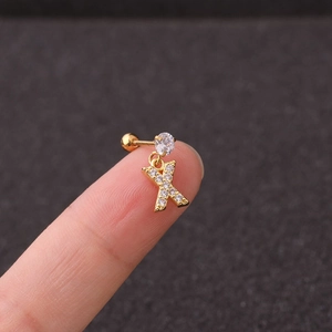 Detail of a gold letter X stud earring with cubic zirconia held by fingers for scale