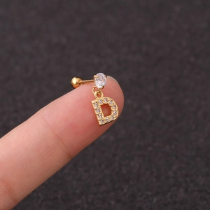 Macro view of a gold-tone earring with a crystal stud and zircon-encrusted D pendant