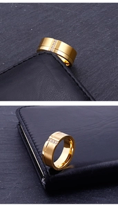 Detail of wide gold-plated ring with brushed finish and three inlaid zircon stones