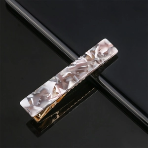Detail of rectangular acrylic hair clip with grey marble pattern on gold metal base