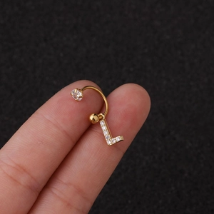 Détail d'un earcuff doré en forme de L avec zircone, présenté sur un doigt de mannequin
