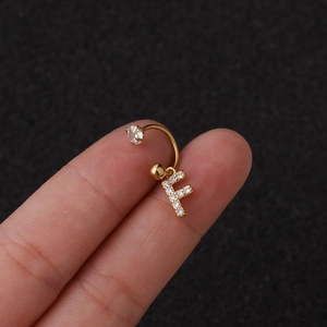 Gros plan d'un piercing de nombril doré avec pendentif lettre F serti de zircons