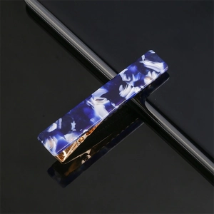 Blue marble texture acetate hair clip with golden metal base on black reflective surface