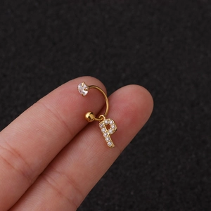 Gros plan d'une boucle d'oreille dorée avec pendentif lettre P et zircone