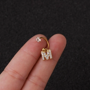 Vue macro de la boucle d'oreille C en acier doré avec pendentif lettre M zircon