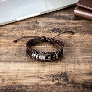 Men's retro braided leather bracelet with metal beads on a business desk setting