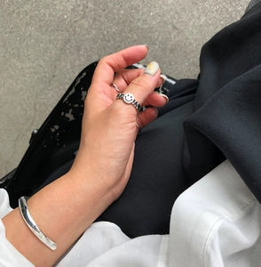 Macro detail of 925 silver smile face ring and minimalist cuff bracelet worn on hand